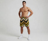 Man wearing a black, yellow, and white striped swimsuit on a plain background