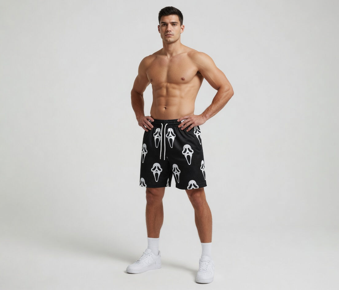 Man wearing black shorts with white patterns on a plain background