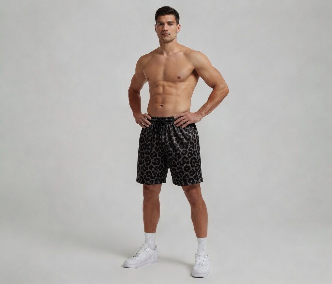 Man wearing black patterned shorts on a plain background
