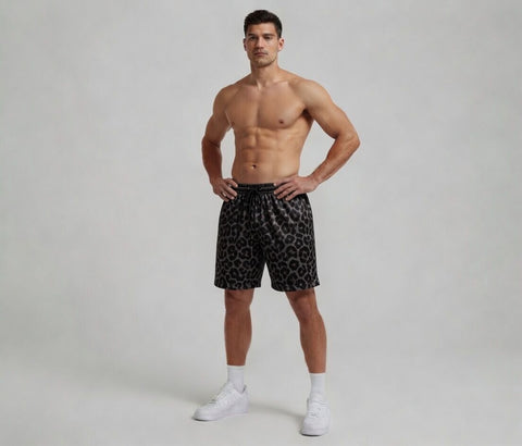 Man wearing black patterned shorts on a plain background